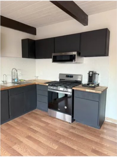 Remodeled kitchen with black cabinets and wood flooring
